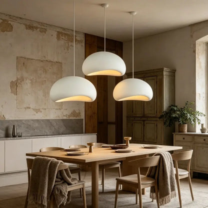 Three modern white and gray high polymer pendant lights with a dome shape hang above a dining table for contemporary interiors