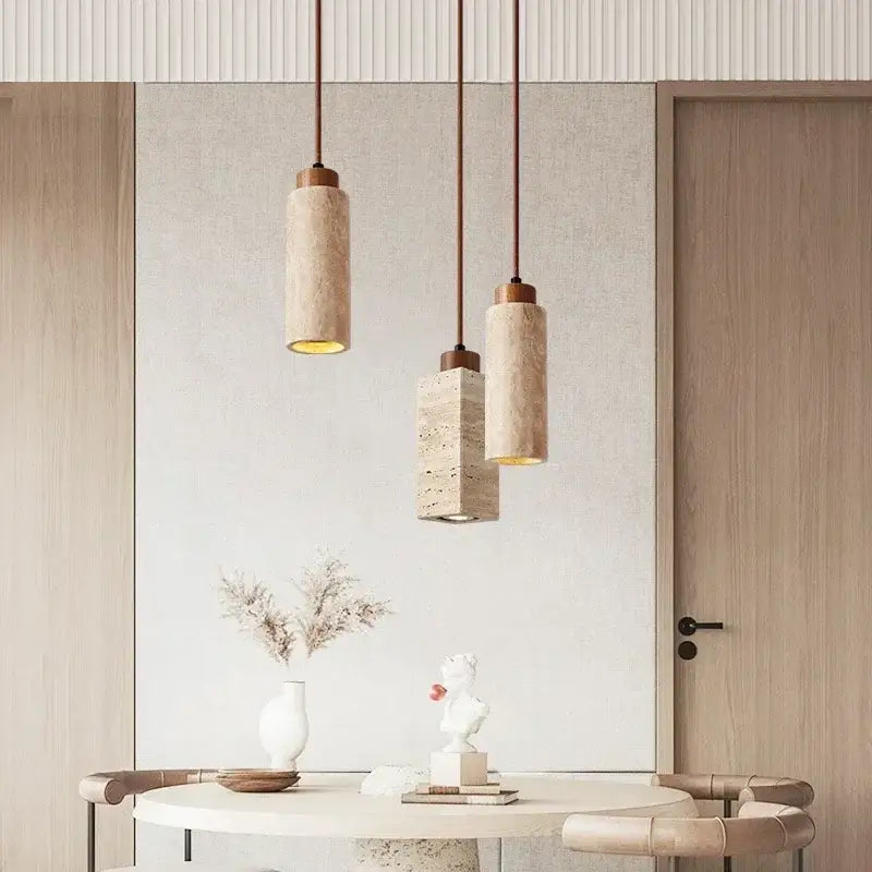 Three modern pendant lights with yellow marble stone shades and brass hardware hang above a minimalist dining table
