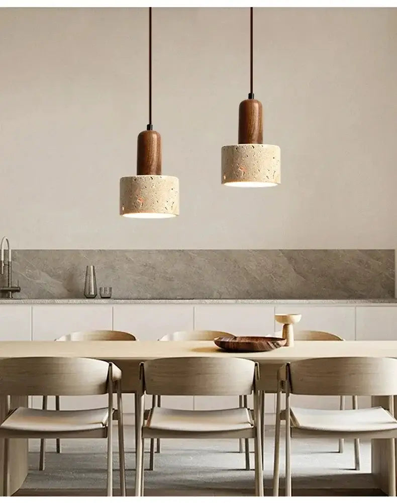 Two minimalist wabi sabi yellow stone pendant lights with cylindrical concrete shades hang above dining table