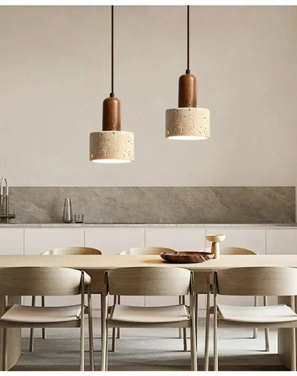 Two minimalist yellow stone pendant lights with cylindrical concrete shades hang above a dining table