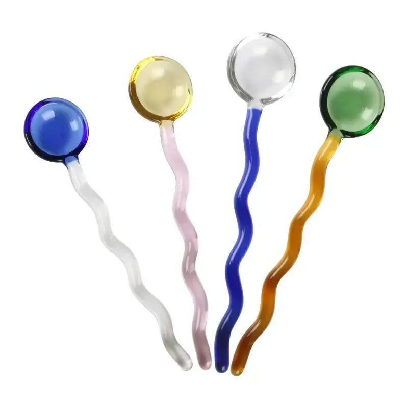 Set of four colorful wavy glass spoon coffee stirring rods in blue yellow clear and green for kitchen use