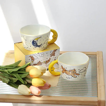 Off-white bear moon ceramic mug with yellow crescent moon handle and whimsical sleeping moon and jumping bear design