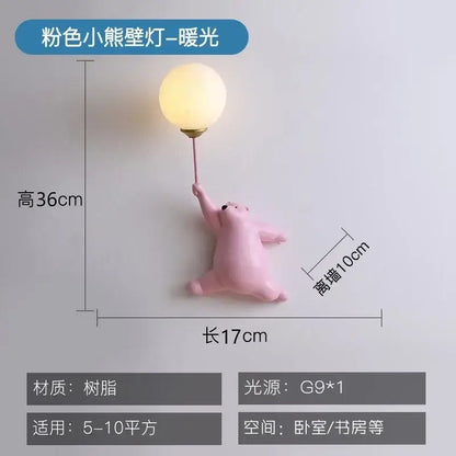 Whimsical pink resin bear kids wall lamp holding a glowing bulb in a kids wall lamp set for bedroom