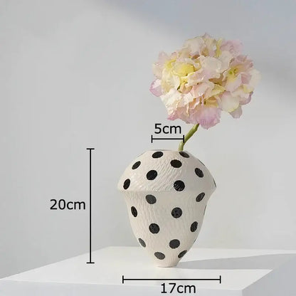 White ceramic wavy vase with black polka dot texture holding pale pink and yellow hydrangeas for living room decor
