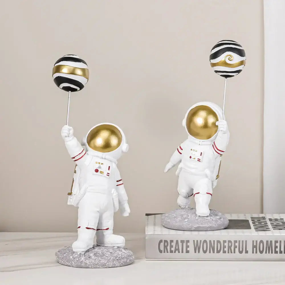 White and gold astronauts figurines with red-trimmed suits holding black and gold balloons for living room decorbites decor