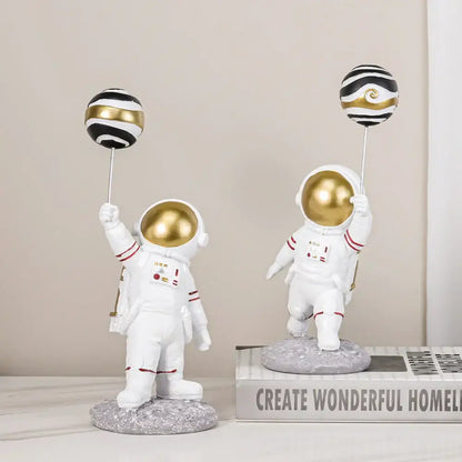 White and gold astronauts figurines with red-trimmed suits holding black and gold balloons for living room decorbites decor