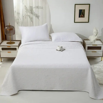 White and gray blue decorbites cotton quilted embroidered bedspread set with textured woven pattern draped on mattress