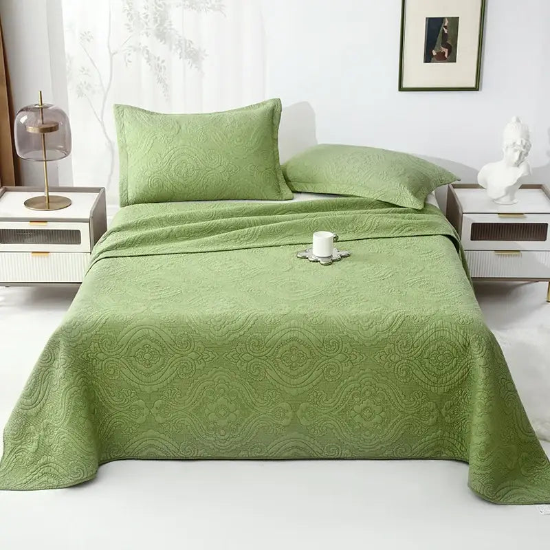 A soft sage green decorbites cotton quilted bedspread set with intricate floral embroidered scrollwork pattern