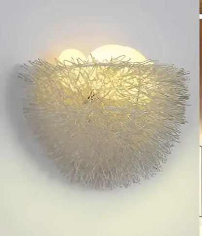 A delicate silver-toned led wall lamp with a woven wireframe nest design for bedroom decorative lighting