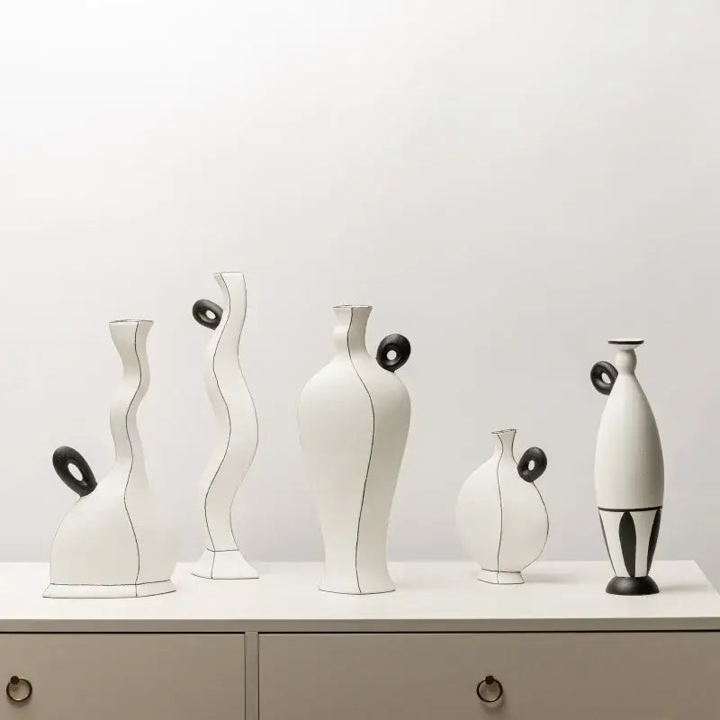 A set of six minimalist white ceramic vases with geometric black lines and black circular accents for living room decor