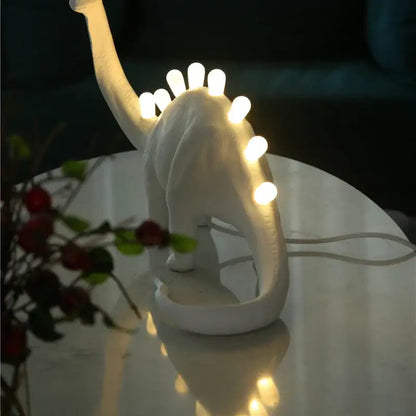 White brontosaurus t-rex dinosaur resin led desk lamp with glowing bulbs along its back for bedroom use
