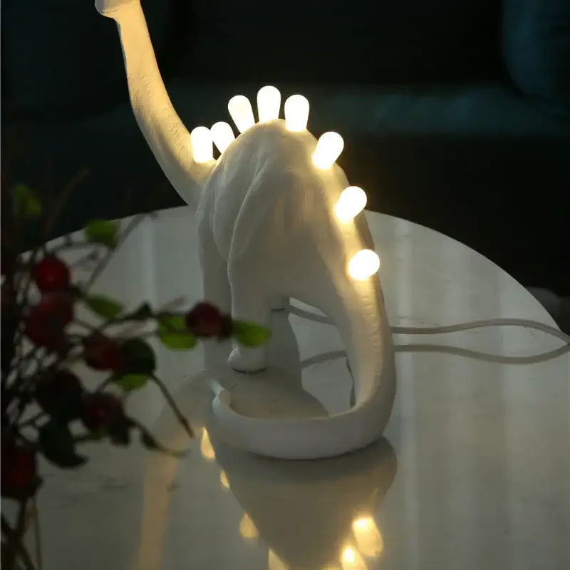 White brontosaurus t-rex dinosaur resin led desk lamp with glowing bulbs along its back for bedroom use