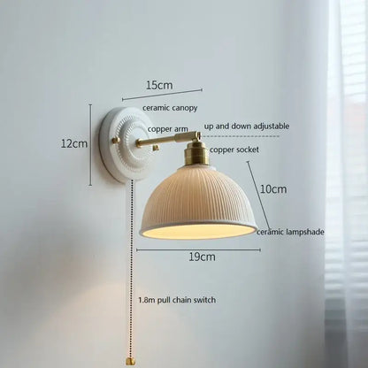 Cream-colored butterfly ceramic led wall lamp with vertical ridges mounted on brass copper arm for bedroom sconce