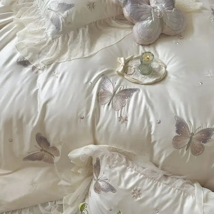Cream-colored quilted bedding set with decorbites butterfly lace ruffles and delicate gray embroidery accents