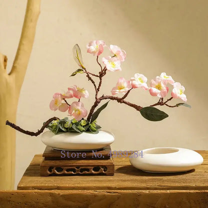 A delicate pink cherry blossom arrangement in a white cobblestone deformation ceramic bonsai pot for living room decor