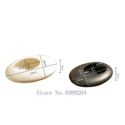 Two oval-shaped ashtrays with polished surfaces in cream and dark gray complement decorbites cobblestone deformation ceramic vase