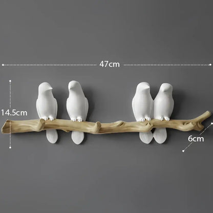 White decorbites bird resin hanger with two white ceramic birds perched on a rustic wooden branch wall decor