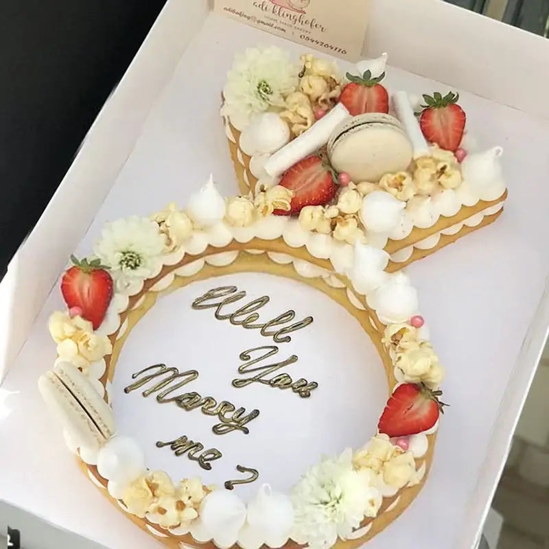 White frosted diamond ring cake made with a ring cake mold decorated with strawberries popcorn meringues and flowers