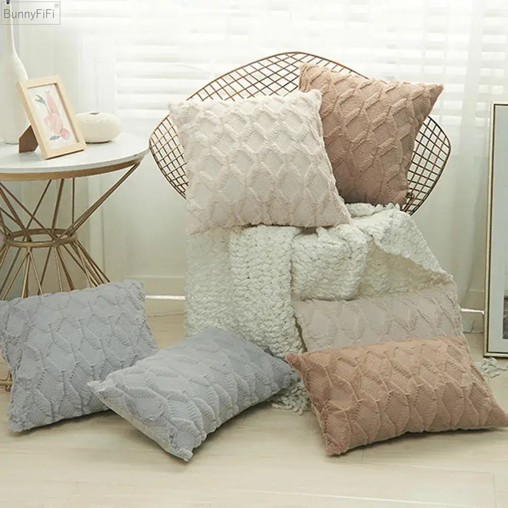 A cozy collection of white embroidered diamond cushion covers in soft beige, gray, and dusty rose plush fabric