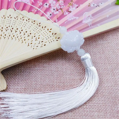 A delicate white jade lotus tassel decorative pendant with carved floral design and silver-threaded fringe for living room decor