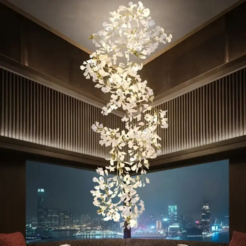 A cascading white orchid decorbites ginkgo chandelier with gold stems suspended above a cityscape living room pendant light