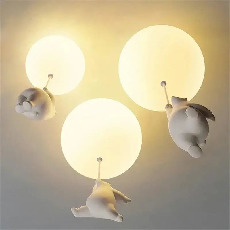 Three white ceramic polar bear pendant lights holding glowing bulbs as cord pendant fixtures for kids bedroom