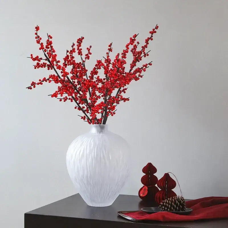 White textured ceramic glass pleats vase holding vibrant red berry branches for living room flower decor