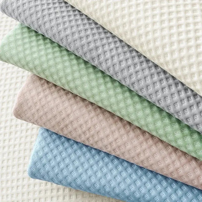 Stack of soft white waffle weave ice silk sofa pads in muted pastel shades including gray mint green beige and light blue