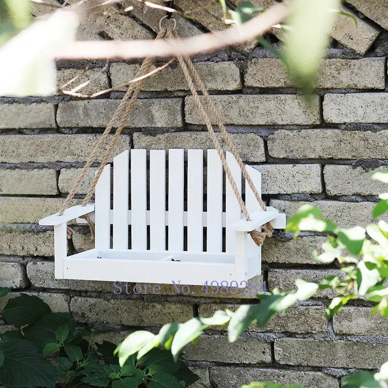 White wooden adirondack bird feeder chair with vertical slats and rope suspension for outdoor garden decor
