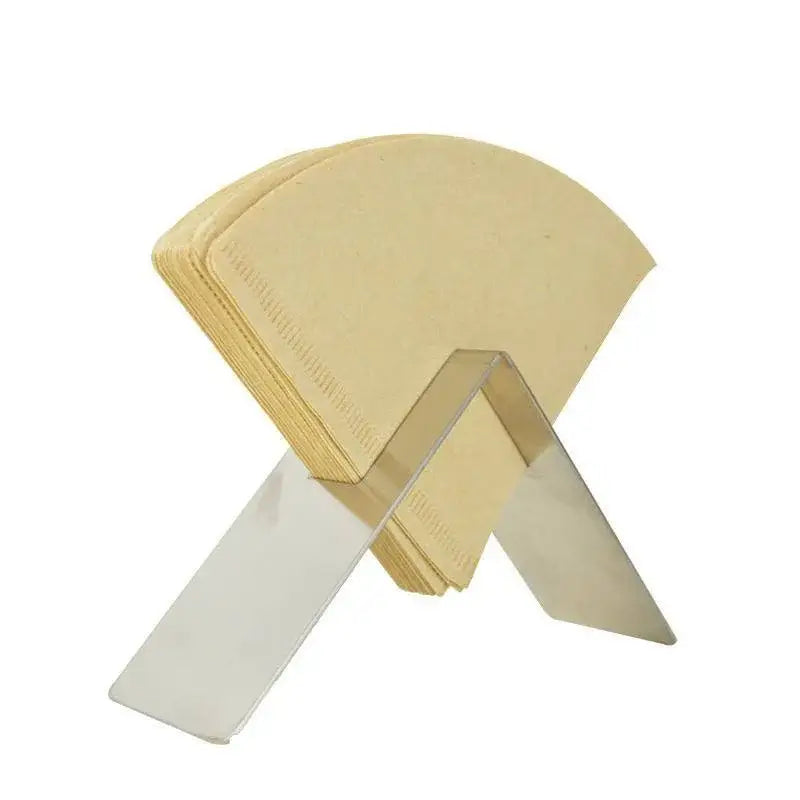 A stack of beige cone paper coffee filters in a clear acrylic stand within a wood and black decorbites barista filter storage box