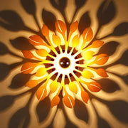 A warm glowing wooden floral sunburst wall lamp with orange and yellow leaf-shaped panels for bedroom lighting