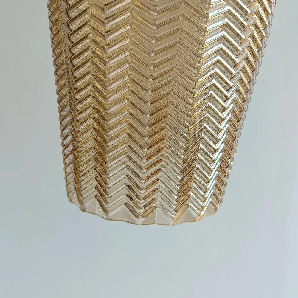 A golden translucent glass pendant light with a distinctive chevron pattern for kitchen and dining rooms