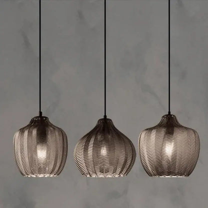 Three woven gold glass pendant lights with textured translucent chevron shades and dark metal frames for kitchen and dining