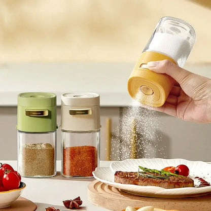 Yellow and clear glass spice dispenser with gold-colored top designed as a kitchen salt grinder