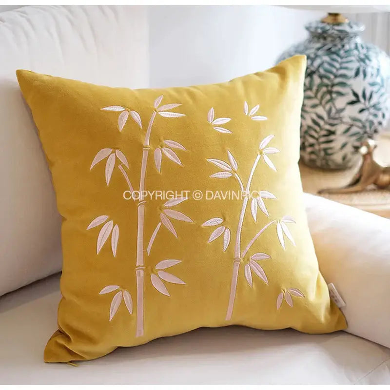 A mustard-yellow velvet throw pillow cover with delicate white embroidered bamboo design for bedroom decor