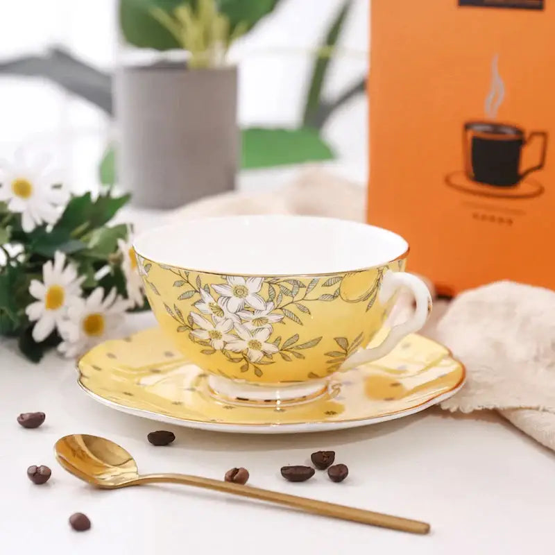 Yellow porcelain teacup with white floral pattern and gold trim on matching saucer from lemon tree bone china set