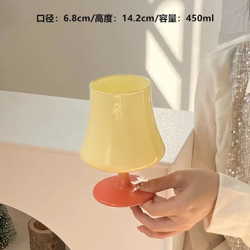 A hand holding a yellow and orange plastic decorbites gem champagne coupe with a flared top from the yellow lime green set