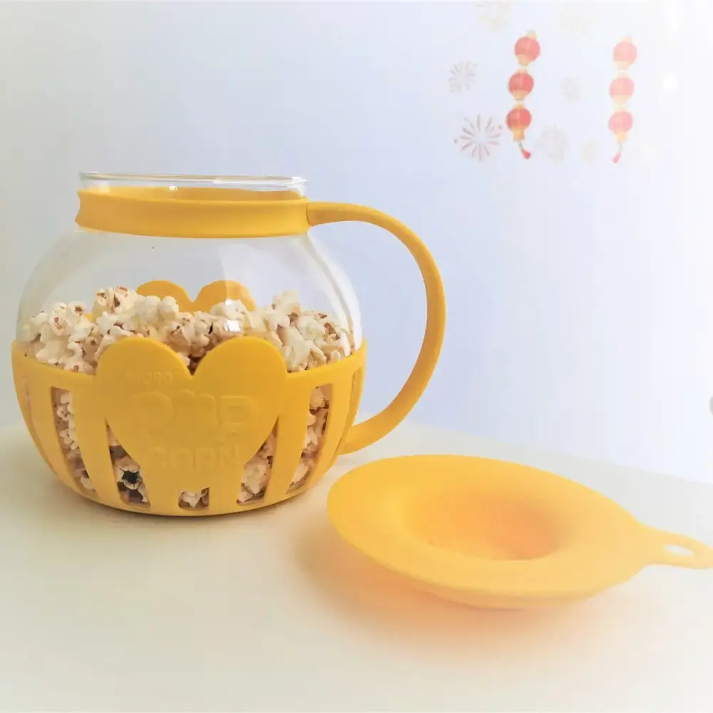 Yellow silicone and clear glass popcorn maker featuring a heart-shaped design and glass jar interior for kitchen use