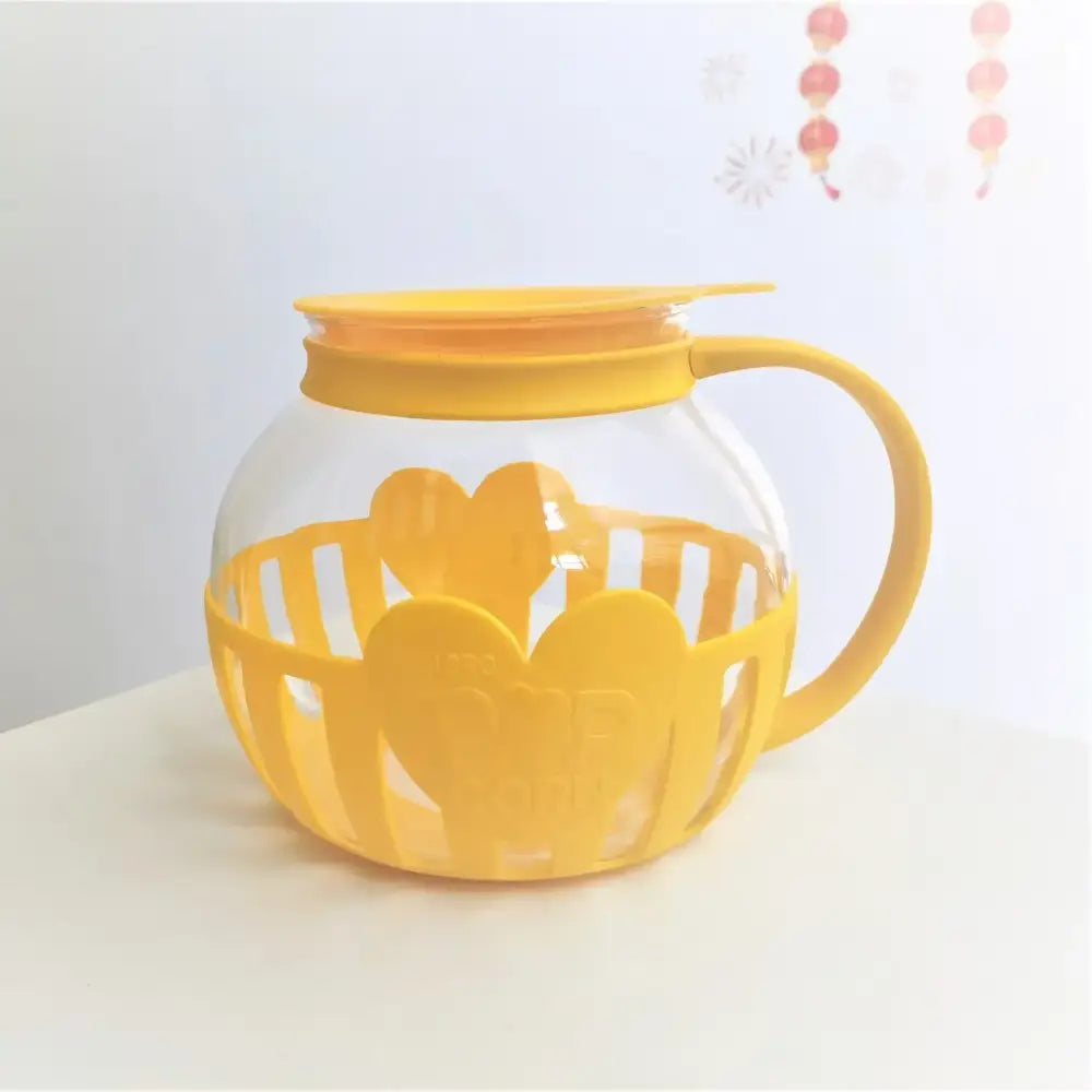 Yellow heart-shaped silicone protective sleeve with clear glass popcorn maker and matching yellow lid for kitchen use