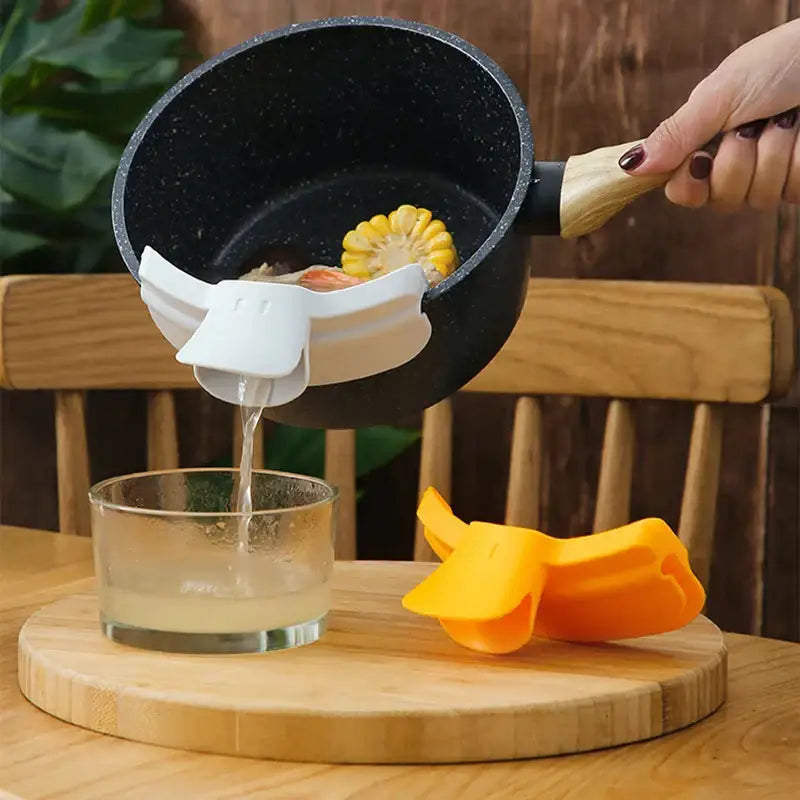 White silicone corn juice extractor with playful decorbites duck beak funnel attached to black speckled pot