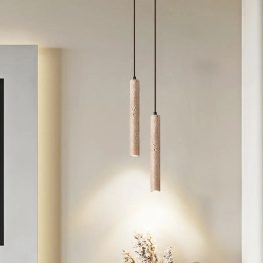 Two minimalist beige stone pendant lights with textured concrete cylindrical shades for bedroom lighting