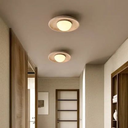 Two circular recessed led ceiling lamps with yellow travertine textured rings and warm frosted glass glow for living room