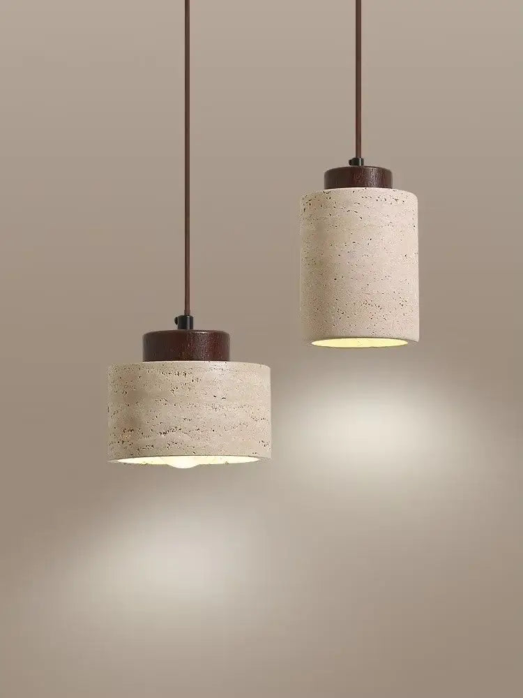 Two cylindrical concrete pendant lights with dark brown wooden tops complement a yellow travertine stone pendant light