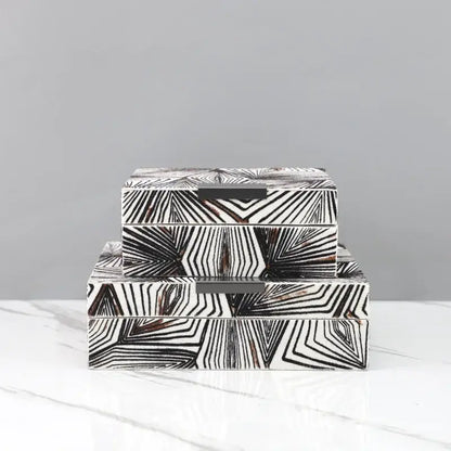 Stacked zebra black and white geometric jewelry storage box with dark metal handles for desktop organization
