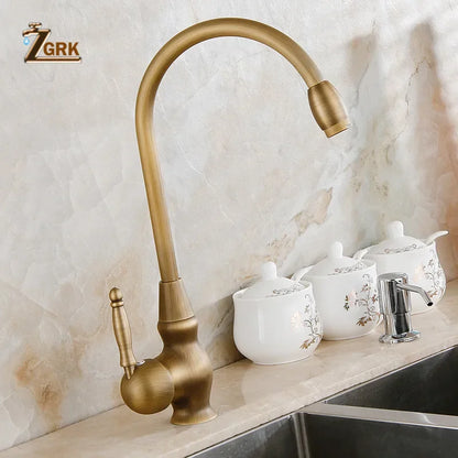Antique brass deck mounted single hole kitchen faucet with curved spout and ornate handle for vessel sink